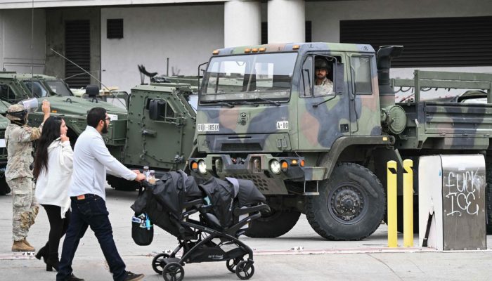 111357176-a-couple-pushes-a-stroller-as-members-of-the-california-national-guard-stand-watch-outside.jpeg